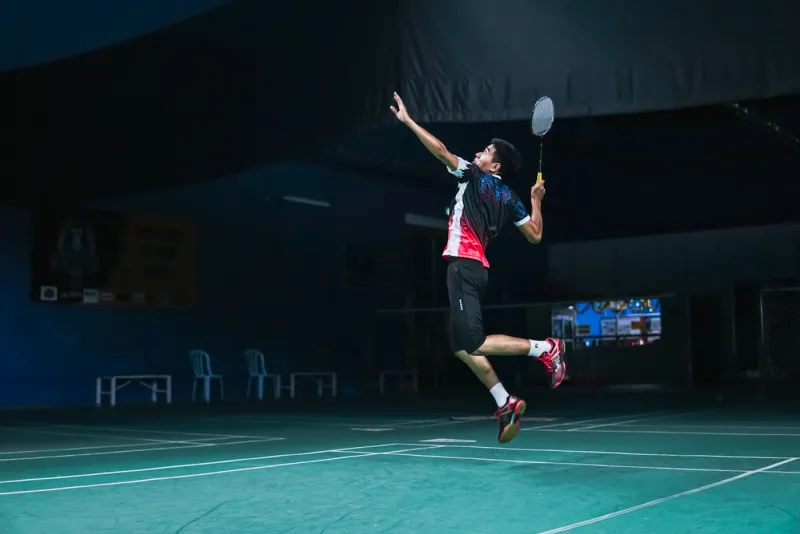 Badmintonista ve výskoku při smeči na badmintonovém kurtu