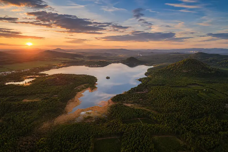 Letecký pohled na Máchovo jezero obklopené borovými lesy za soumraku